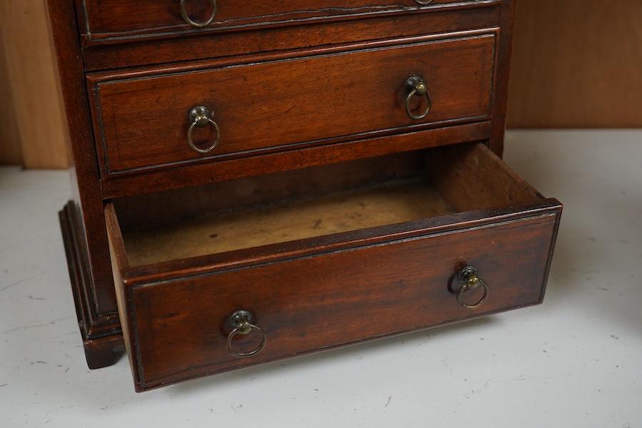 A late Georgian mahogany miniature four drawer chest. 23cm high, 21cm wide. Condition - good